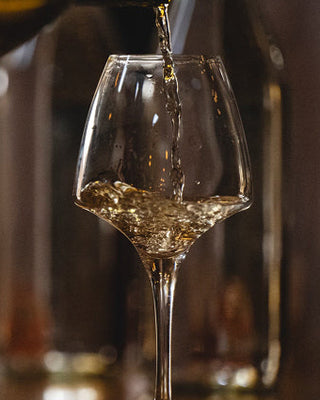 wine being poured into a glass with a blurred background
